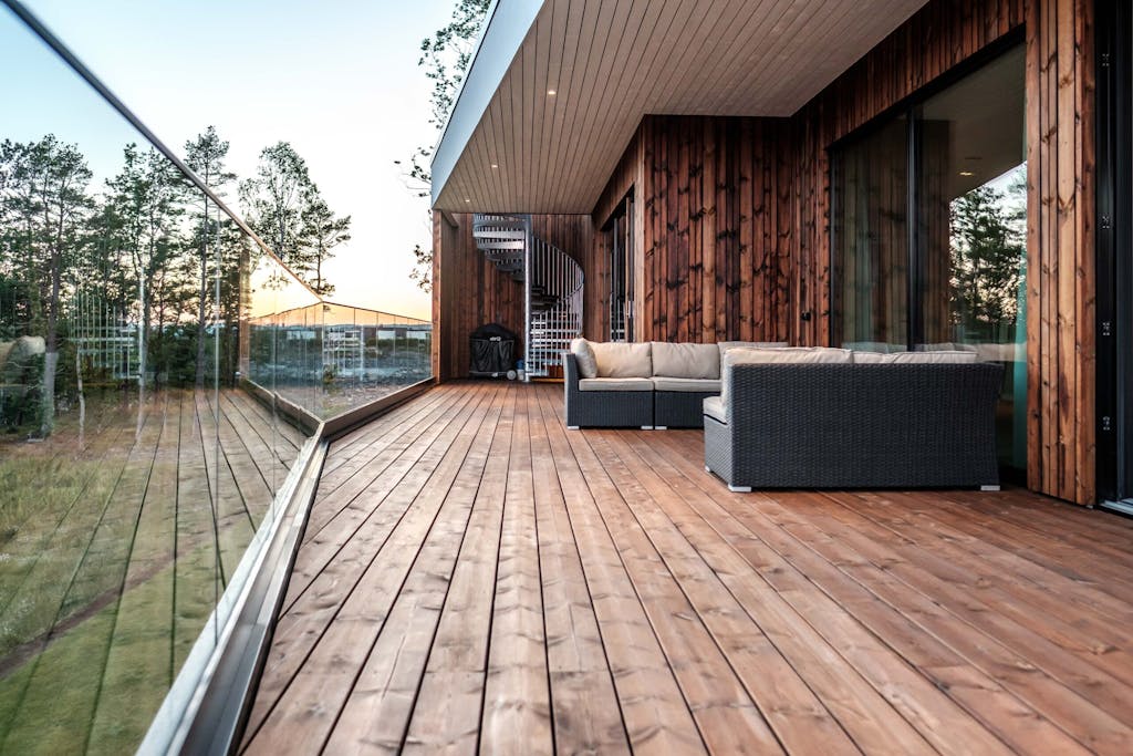 Terrasse med glassrekkverk og utemøbler.